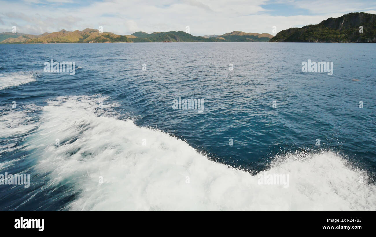 Foam wave of the sea surface from the movement of the ferry. View of the Busanga Mountains. The city of Coron. The Palawan Islands of the Philippines. Stock Photo