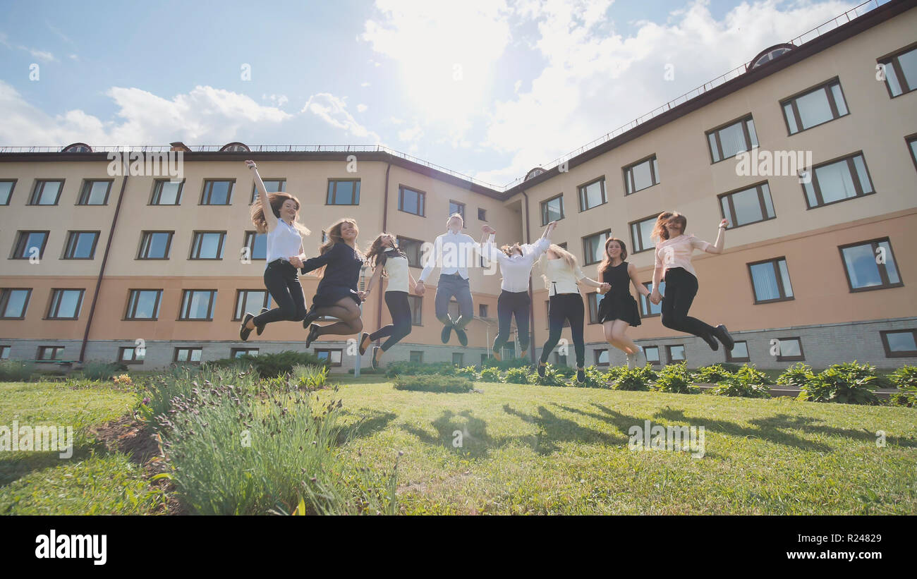 Happy schoolboys graduates jump on the background of their school. Stock Photo