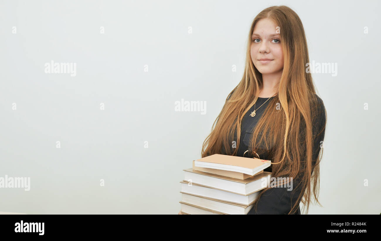 A schoolgirl in a good mood with a pile of books. Stock Photo