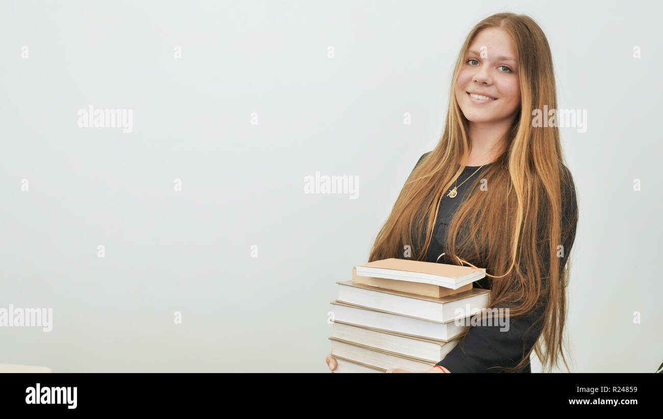 A schoolgirl in a good mood with a pile of books. Stock Photo