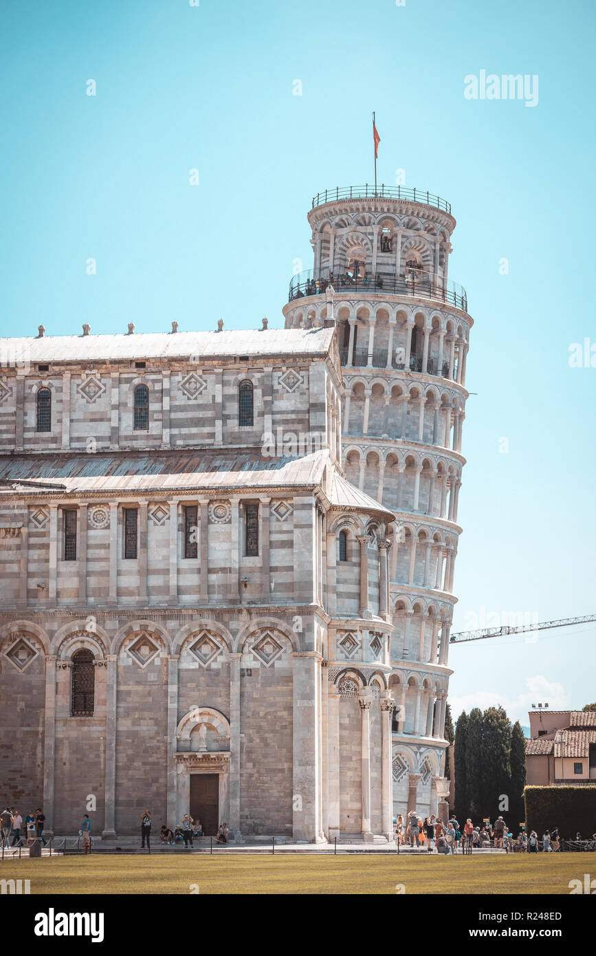 Vertical photo with famous Leaning tower in italian town Pisa. Tower is placed on Piazza dei Miracoli with cathedral in front. Sky is blue without clo Stock Photo