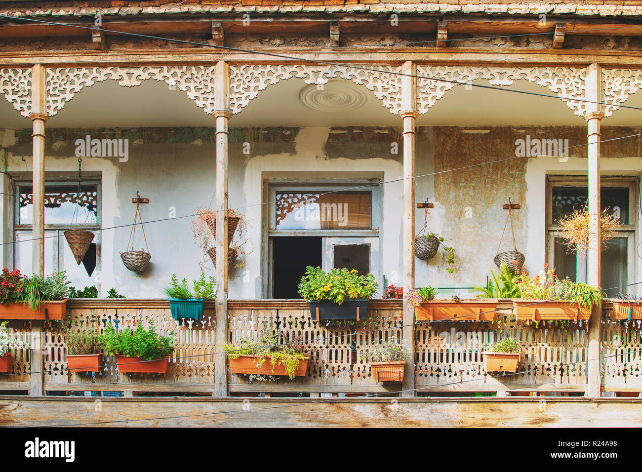 Old House in Tbilisi, Georgia with Beautiful Terrace. Ancient traditional wooden balcony decorated with lot of flowers and old artifacts Stock Photo