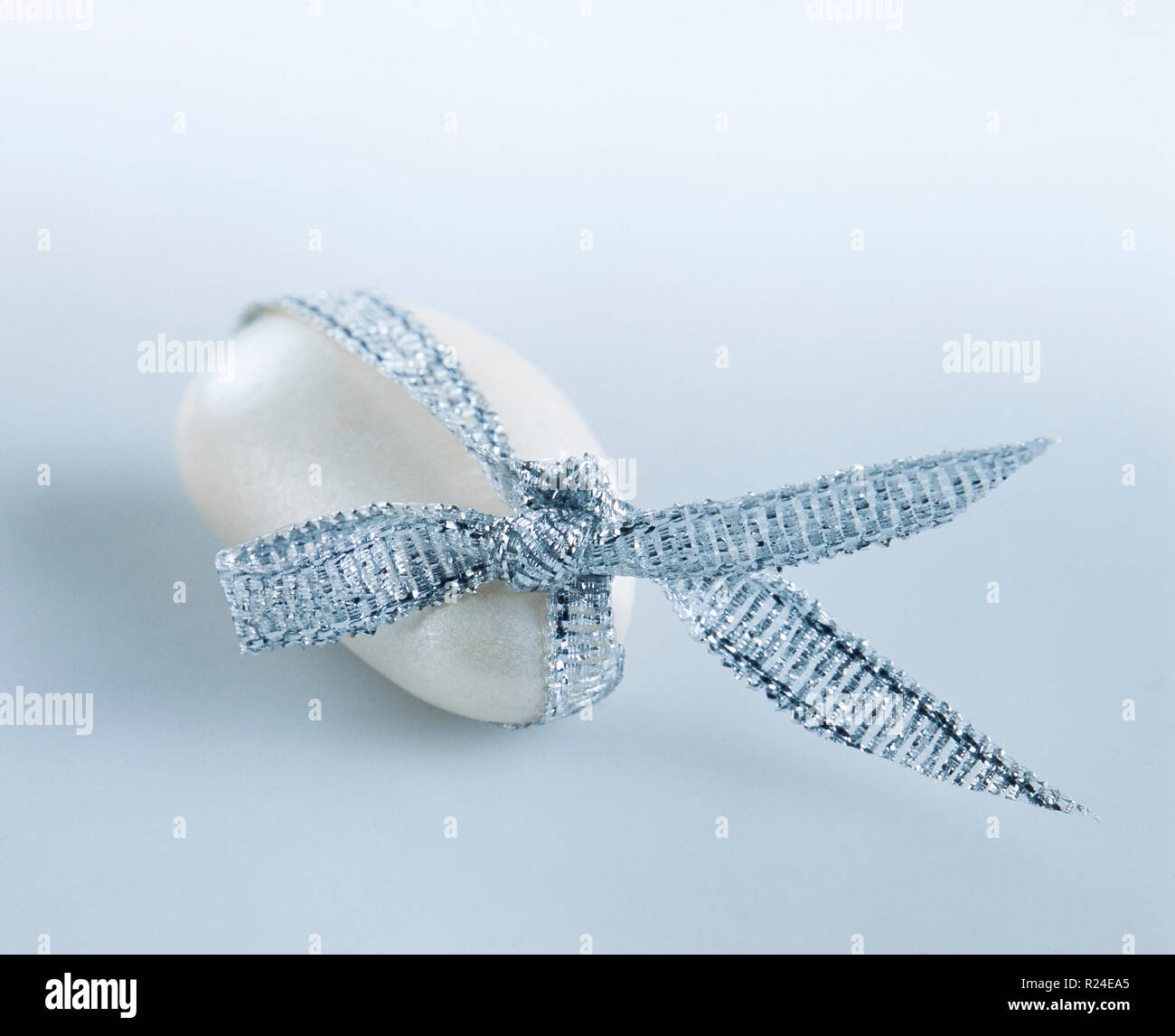 White candy-coated almond tied with a silver ribbon Stock Photo
