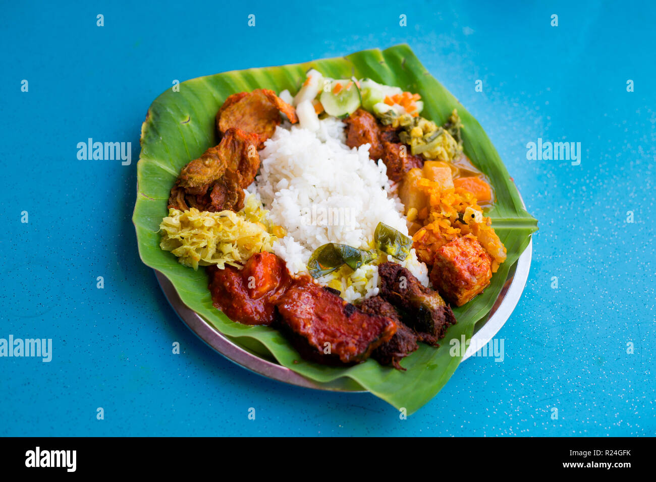 Fresh prepared selection of malaysian local vegetarian indian food served on banana leaf in restaurant in Kuala Lumpur. Traditional asian cuisine made Stock Photo