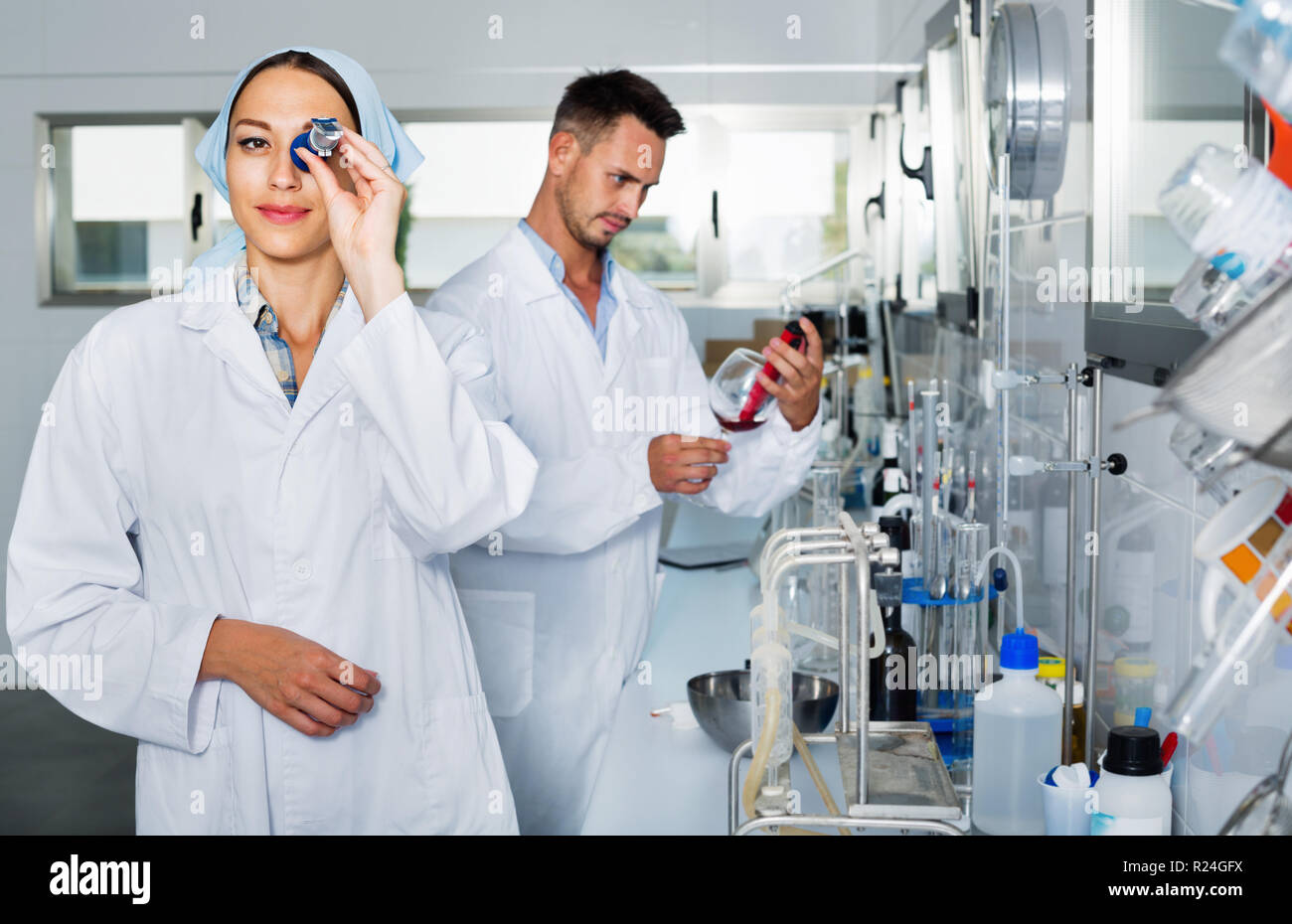 Positive Researcher Two efficient smiling positive researchers in white coat checking wine ...