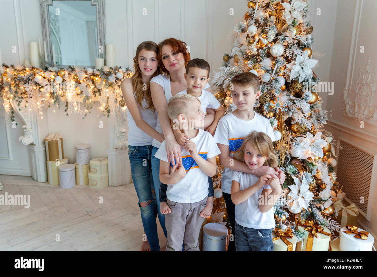 Happy family mother and five children decorating Christmas tree on