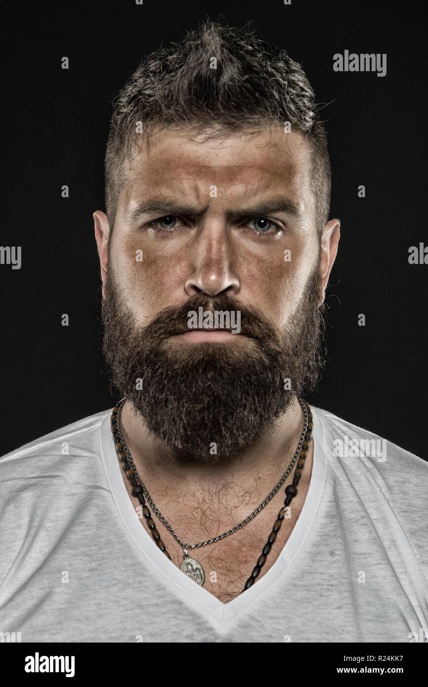 Brutality and masculinity. Man bearded hipster serious face close up. Brutal man with over suntanned skin face. Hipster with beard and mustache looks strict and brutal. Brutal masculine appearance. Stock Photo