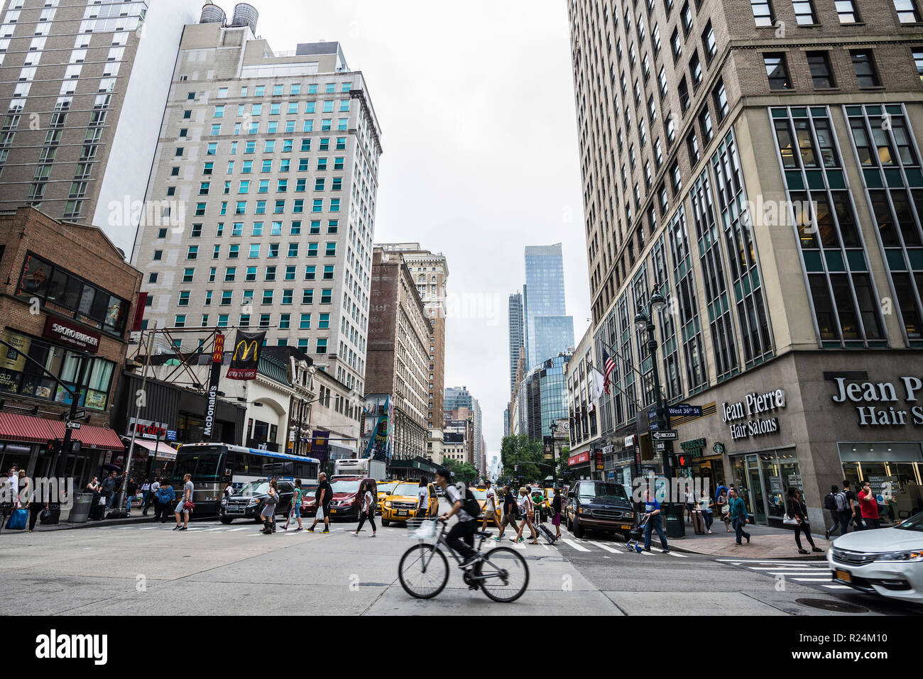 New York City, USA - July 25, 2018: Sixth Avenue (6th Avenue) – officially Avenue of the Americas - with people and cyclist around and traffic in Manh Stock Photo