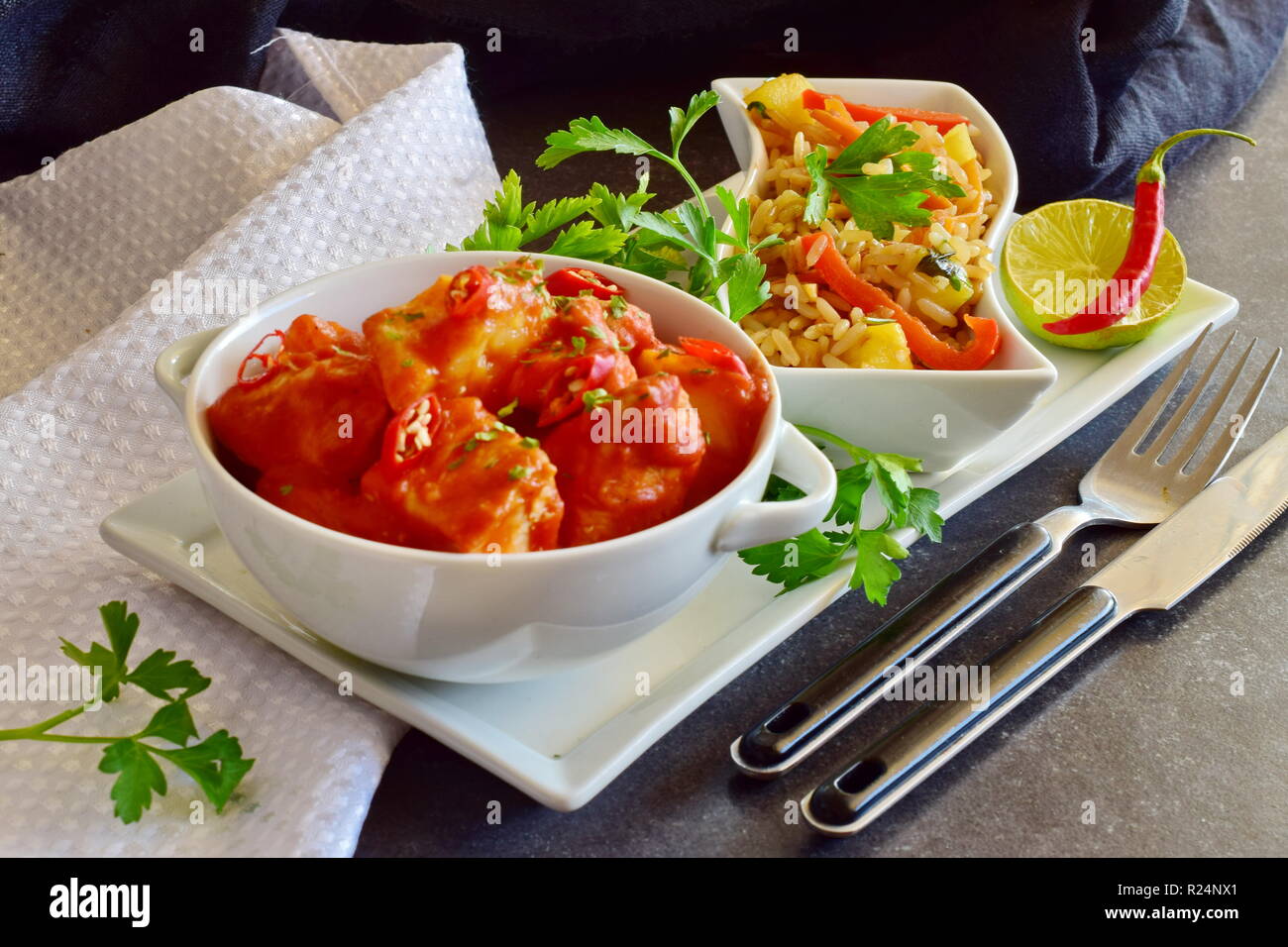 Chicken stew with pineapple and chili tomato sauce in a white bowl served with boiled rice with vegetables. Healthy eating concept Stock Photo