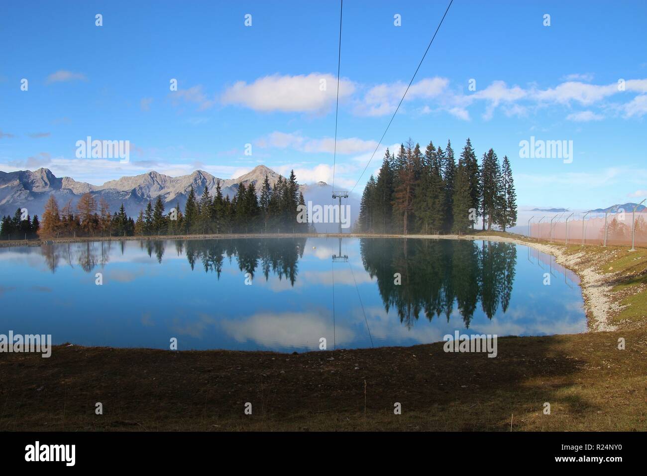 View of a reservoir lake for artificial snow, ski lift and surrounding mountains, in autumn. Height 1300 m. Hinterstoder, Upper Austria, Europe. Stock Photo