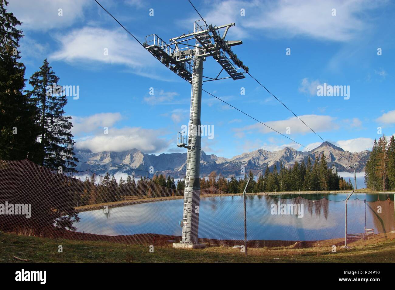 View of a reservoir lake for artificial snow, ski lift and surrounding mountains, in autumn. Height 1300 m. Hinterstoder, Upper Austria, Europe. Stock Photo
