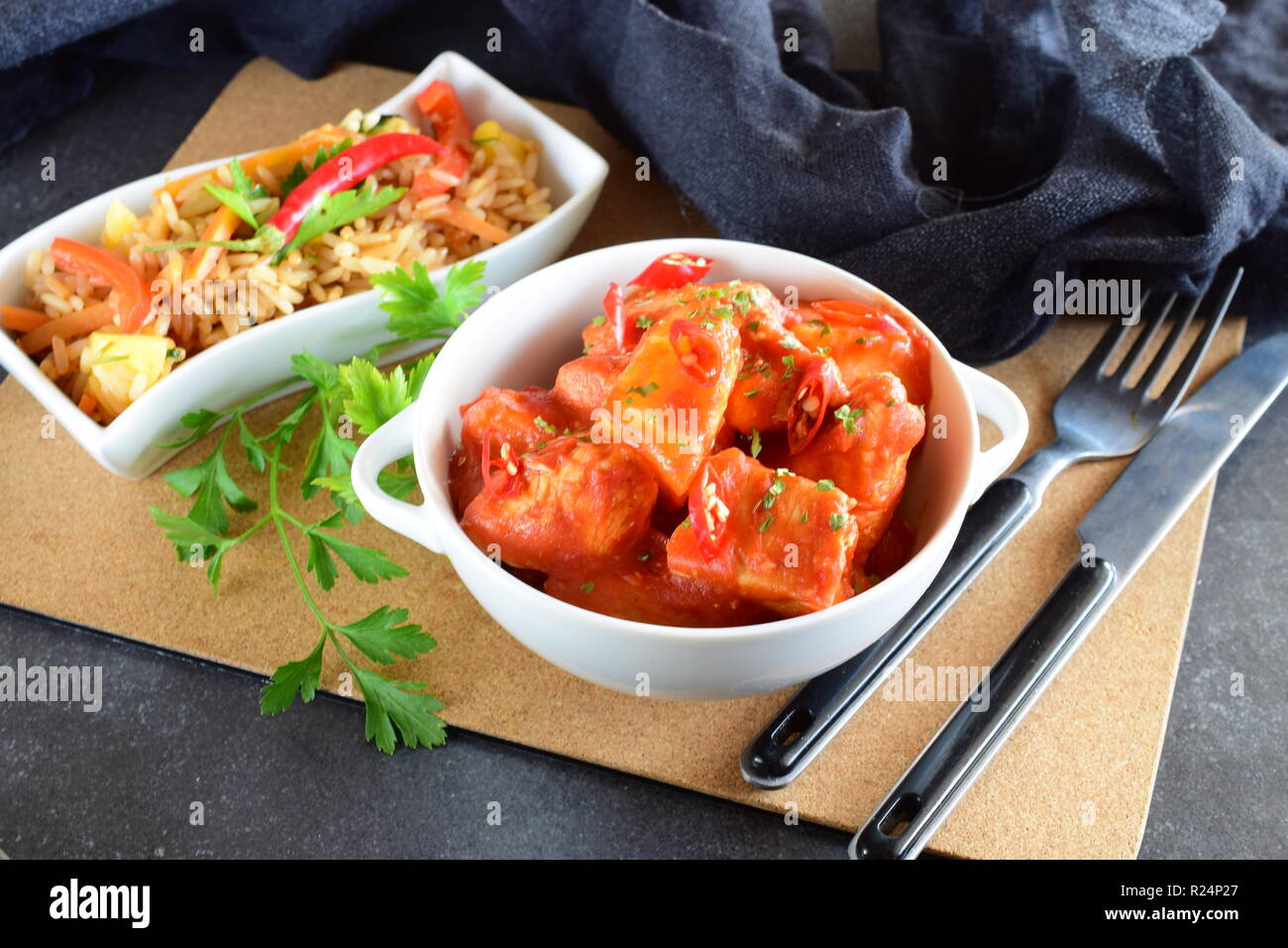 Chicken stew with pineapple and chili tomato sauce in a white bowl served with boiled rice with vegetables. Healthy eating concept Stock Photo