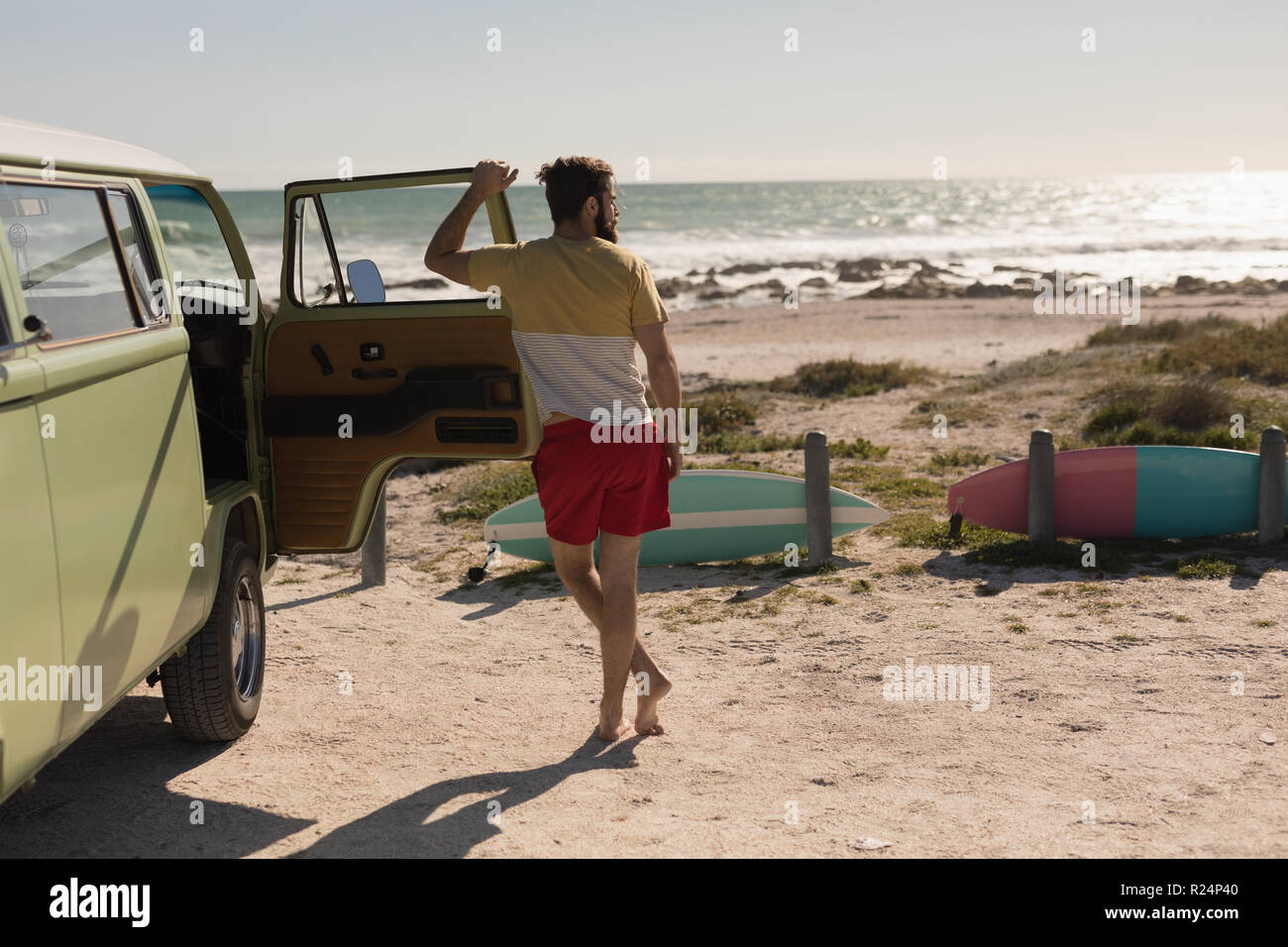 Man leaning on van door near beach Stock Photo
