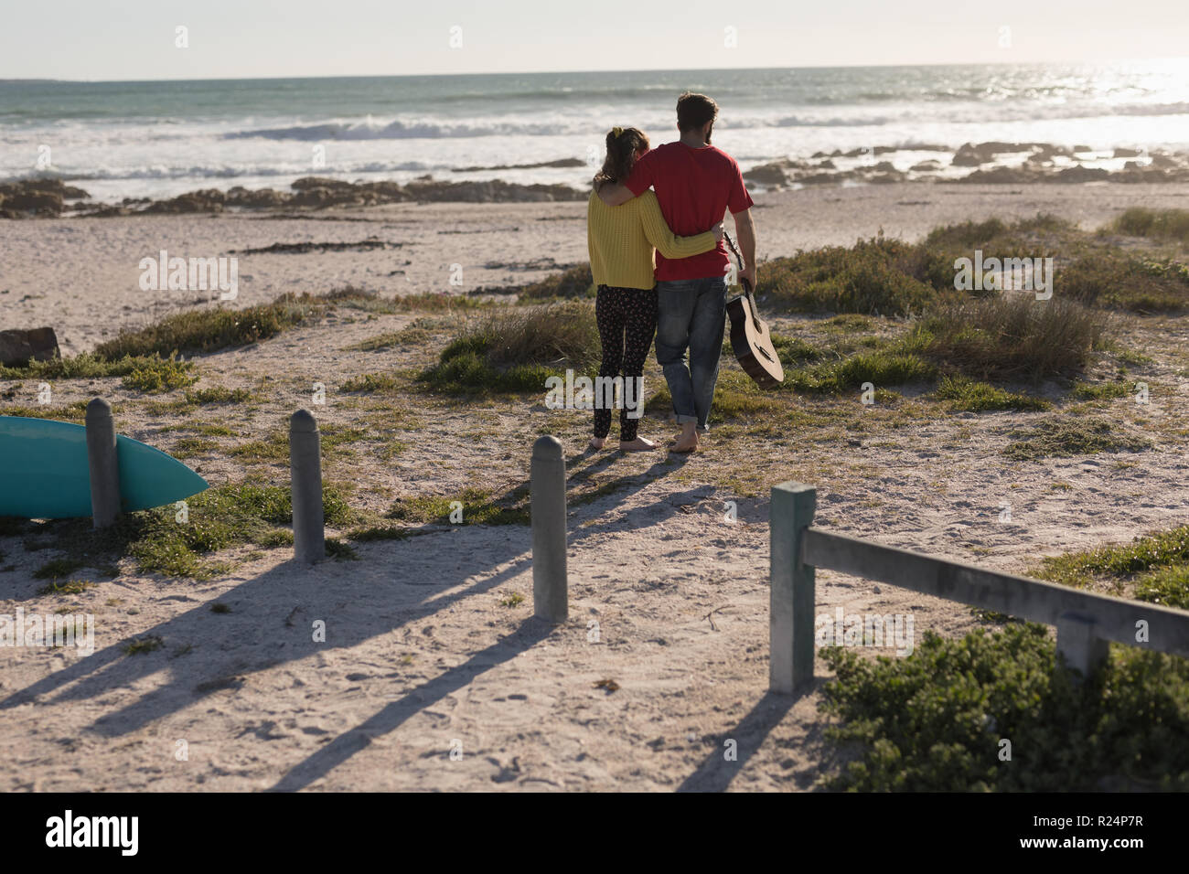 Couple standing with guitar on beach Stock Photo