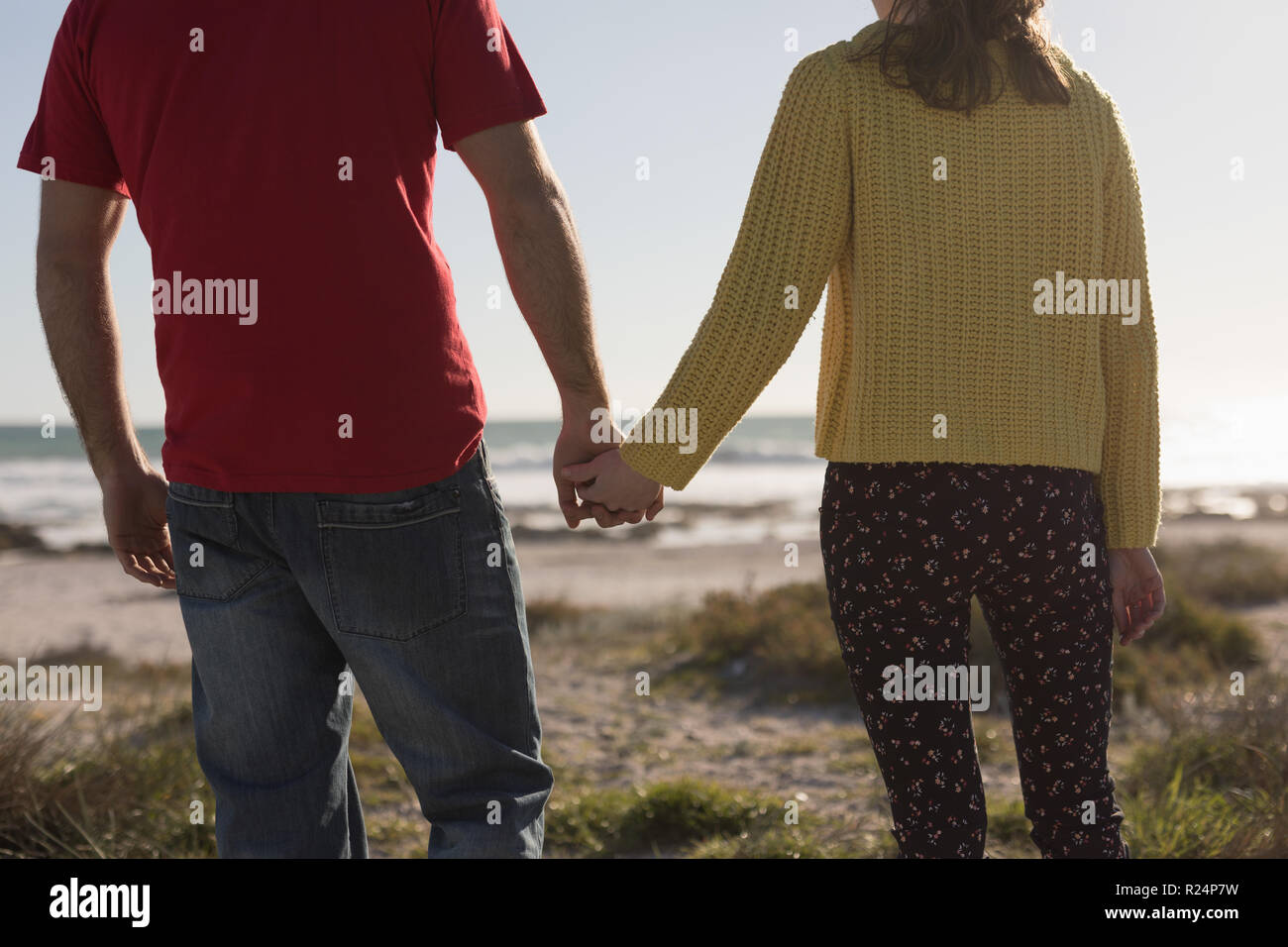 Couple holding hands and standing on beach Stock Photo