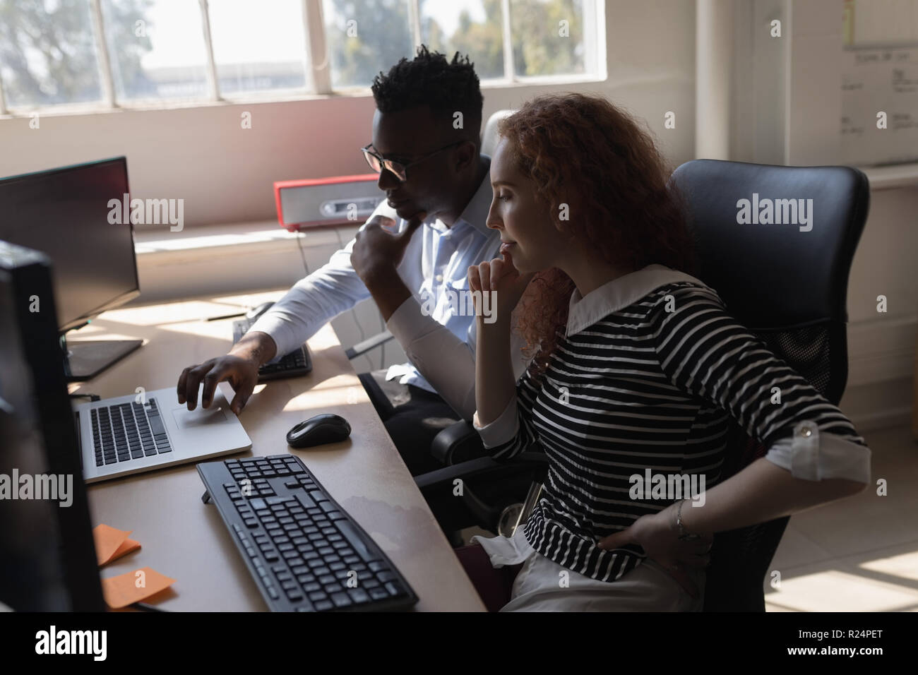 Executives discussing over laptop at desk Stock Photo