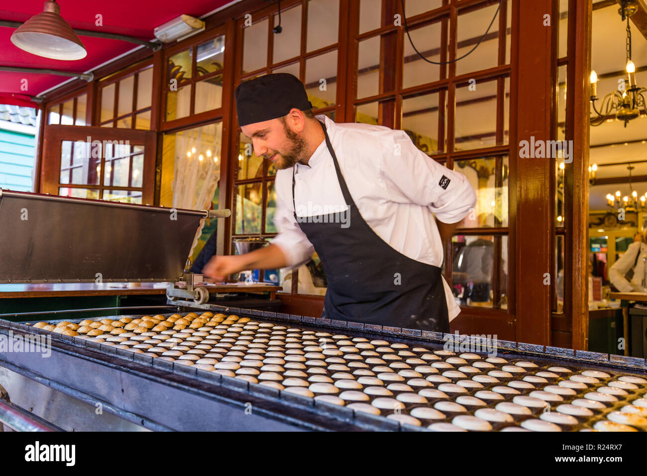 Arnhem,Netherlands- November, 04, 2018: Man baking traditional Dutch poffertjes in an old Poffertjes stall Stock Photo