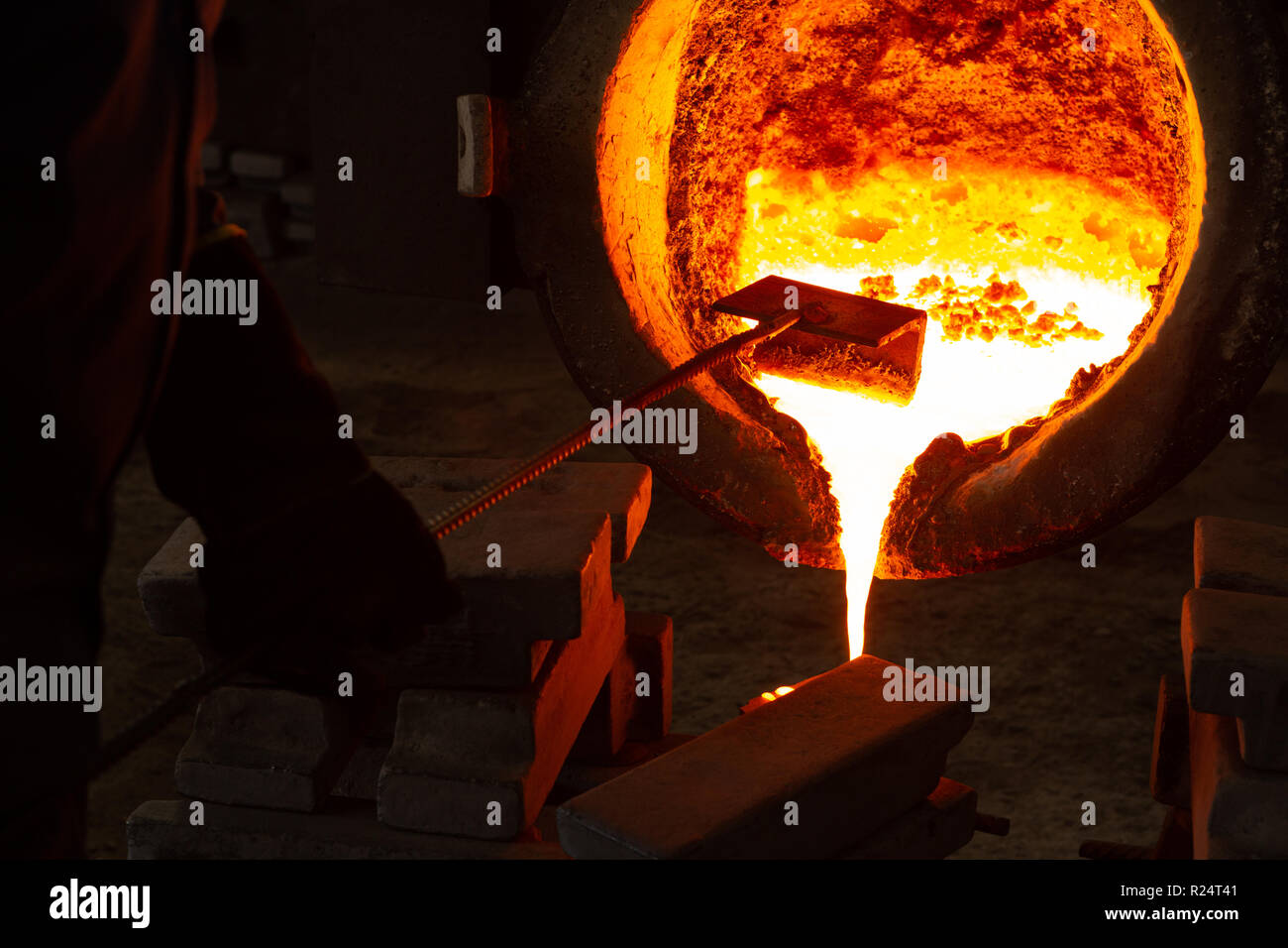 Workers pouring molten metal from flasks into moulds Stock Photo