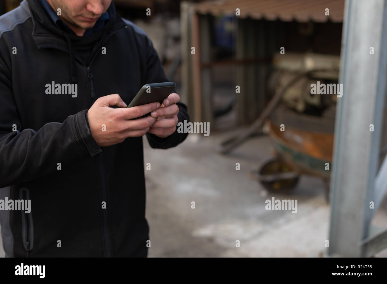 Man using mobile phone in foundry workshop Stock Photo