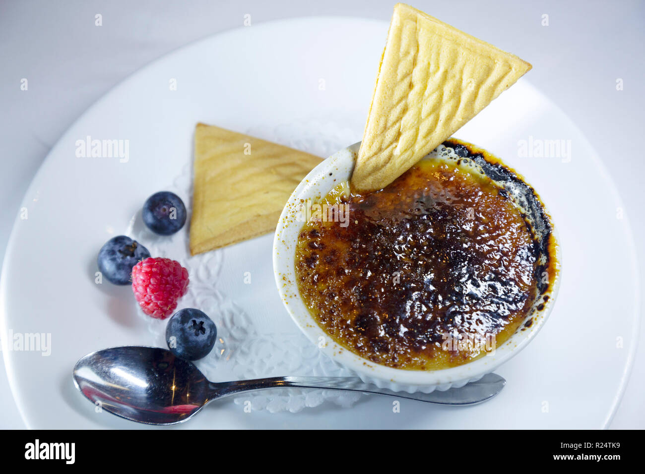 Creme Brulee served with wafers and seasonal fruit in Quebec, Canada. The dessert has a hard glaze. Stock Photo