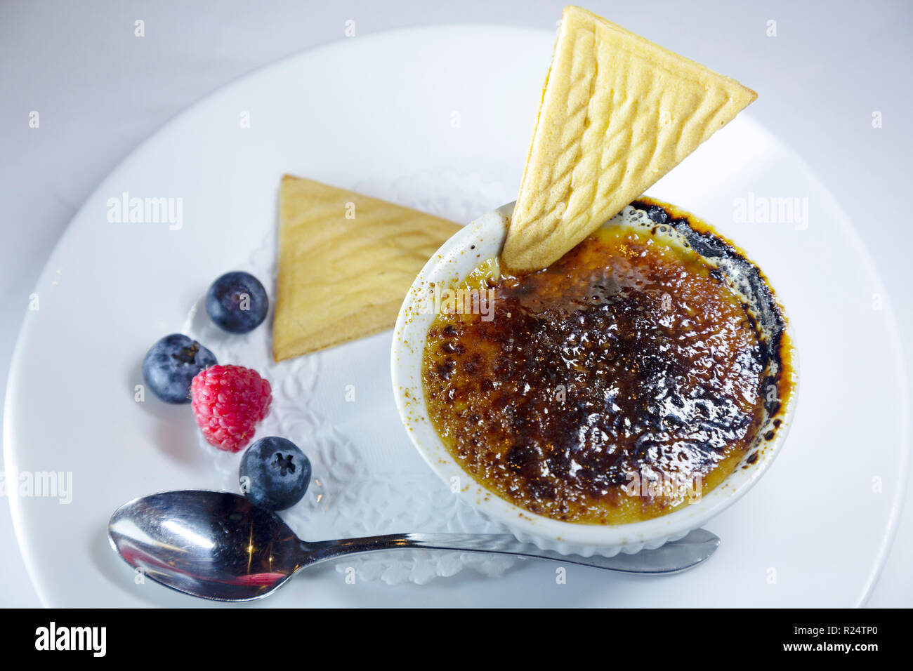 Creme Brulee served with wafers and seasonal fruit in Quebec, Canada. The dessert has a hard glaze. Stock Photo