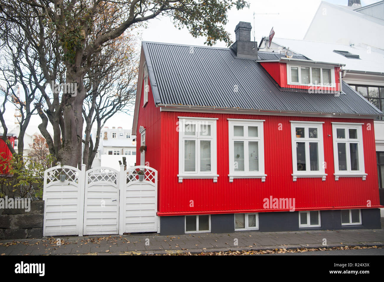 Building facade with red wall and white window frames. Architecture design concept. Scandinavian house design and nordic style. Red stylish house. Bright house at usual scandinavian street cloudy day. Stock Photo