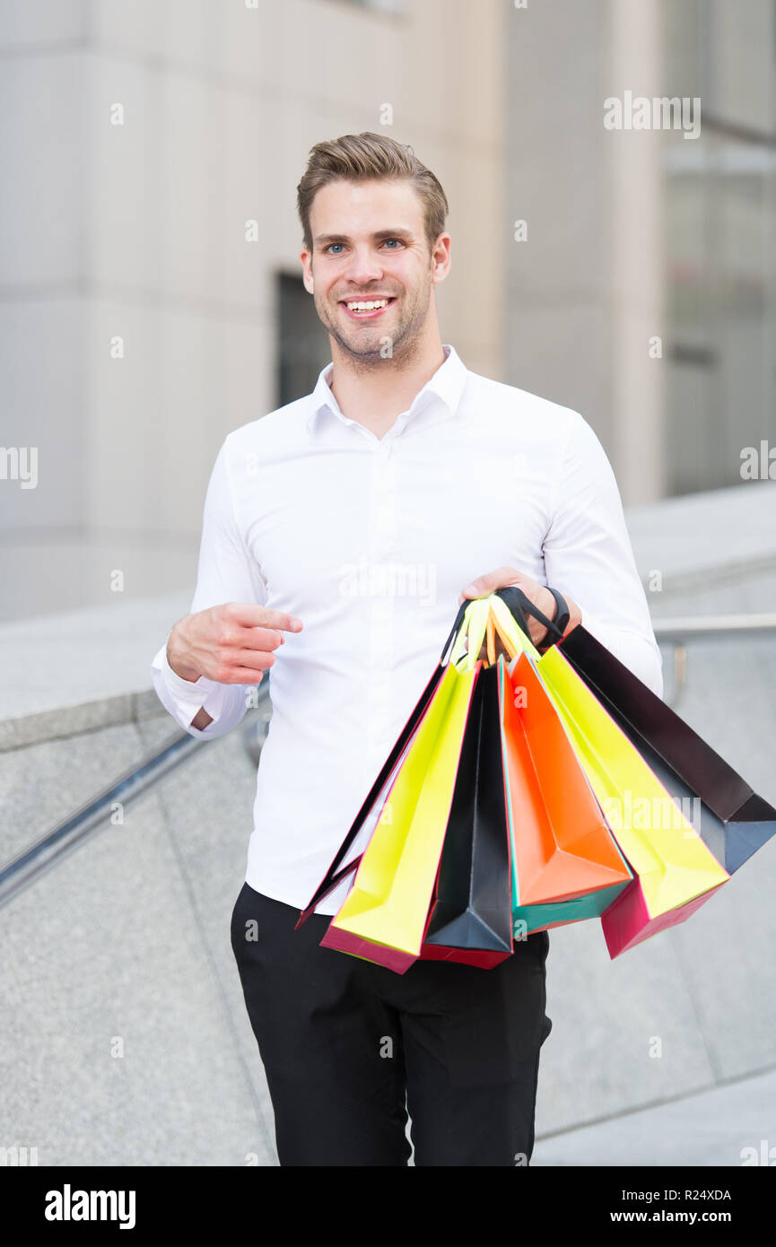 Man formal clothes carry shopping bags. Guy happy carry bunch shopping bags. Profitable deals on black friday. Man hold lot paper bags packages after shopping in mall. Black friday sale concept. Stock Photo