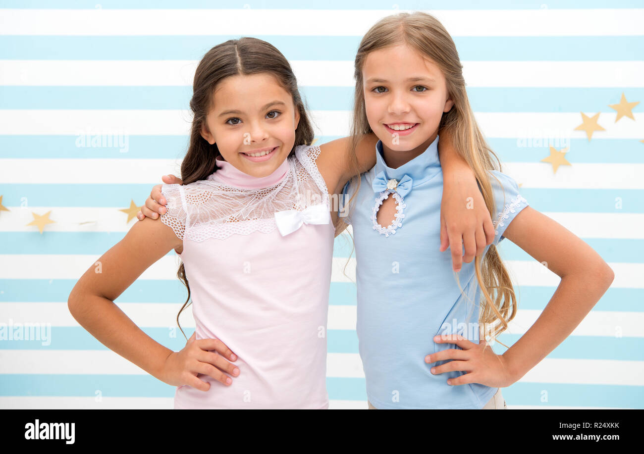 Friendship as treasure concept. Kids schoolgirls preteens happy together. Friendship from childhood. Girls smiling happy faces hug each other stand striped background. Girls children best friends hug. Stock Photo