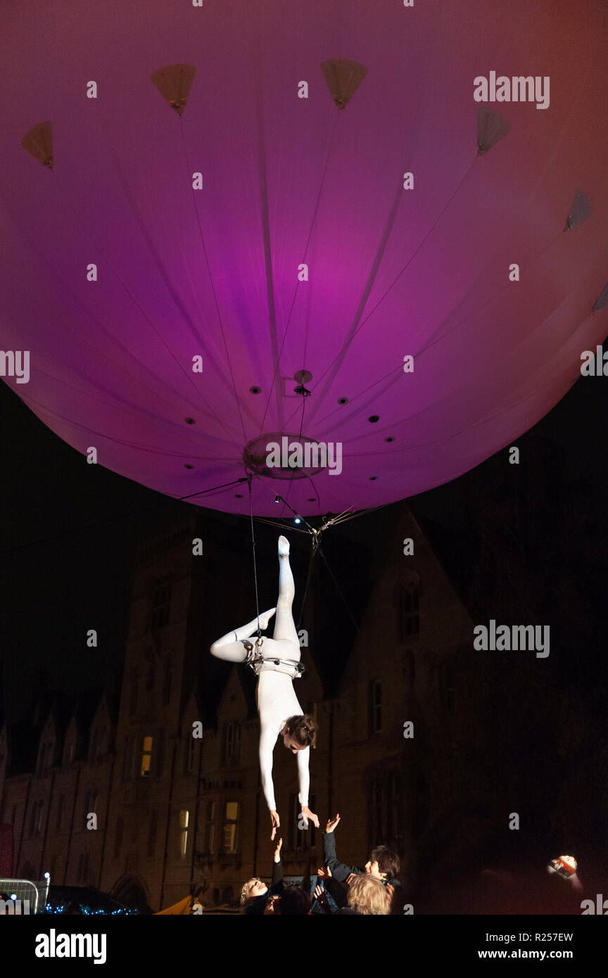 Oxford, UK. 16th November 2018. A female acrobat dances high above Broad Street, Oxford as part of the city's Christmas Festival of Lights, suspended under a colourful balloon. Credit: WALvAUS/Alamy Live News Stock Photo