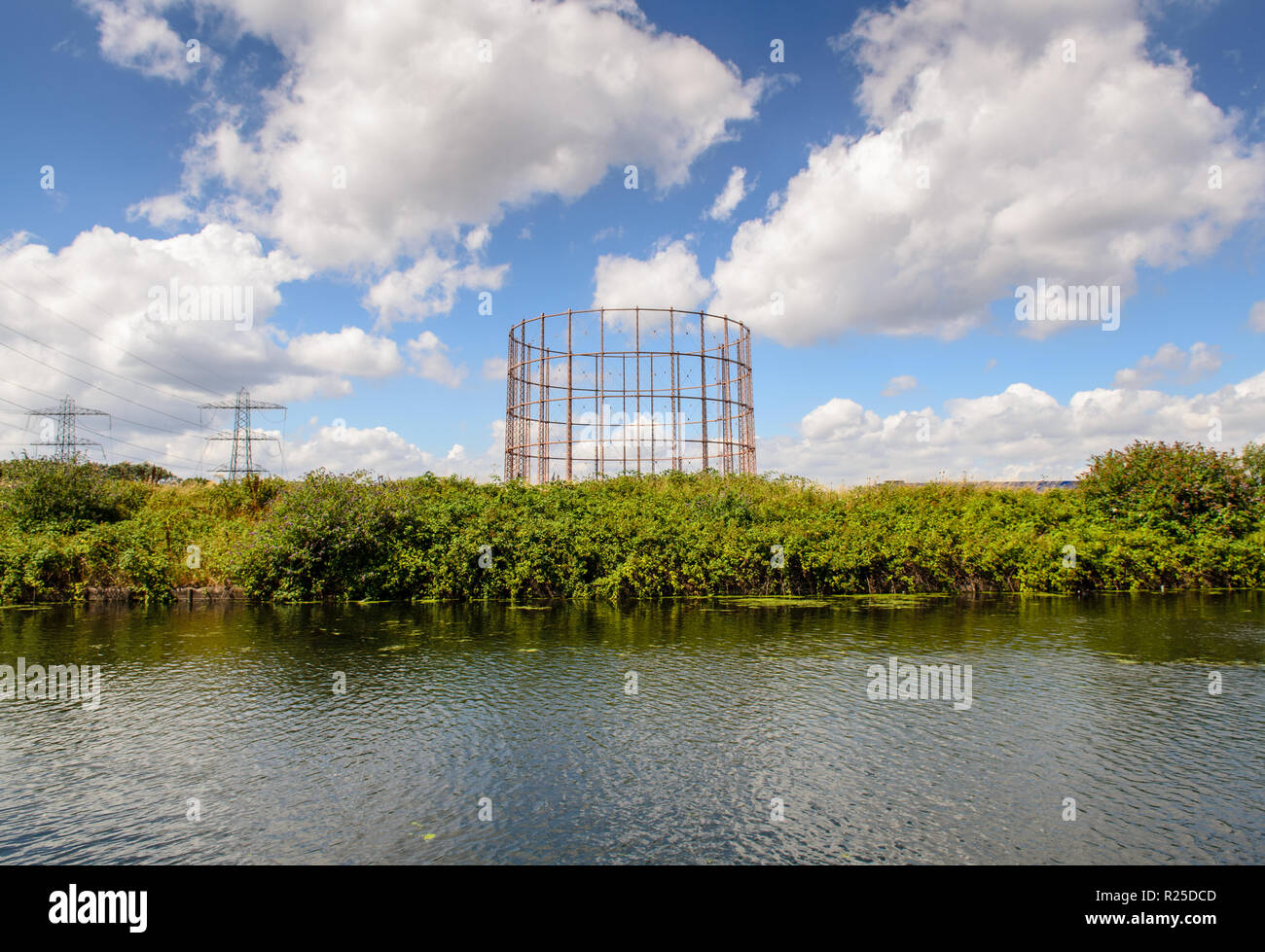 A traditional gasometer stands empty and abandoned on wasteground ...