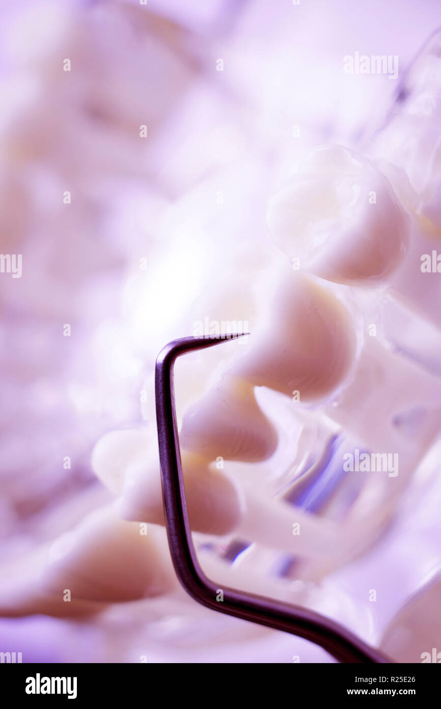 Dentist cleaning teeth with titanium metal tooth pick instrument to