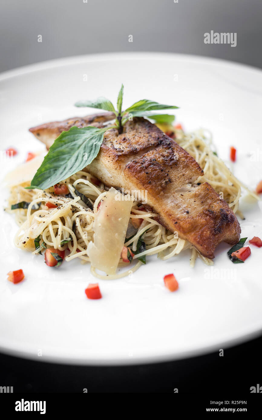 fresh cod fish fillet on mixed vegetable and parmesan spaghetti pasta Stock Photo