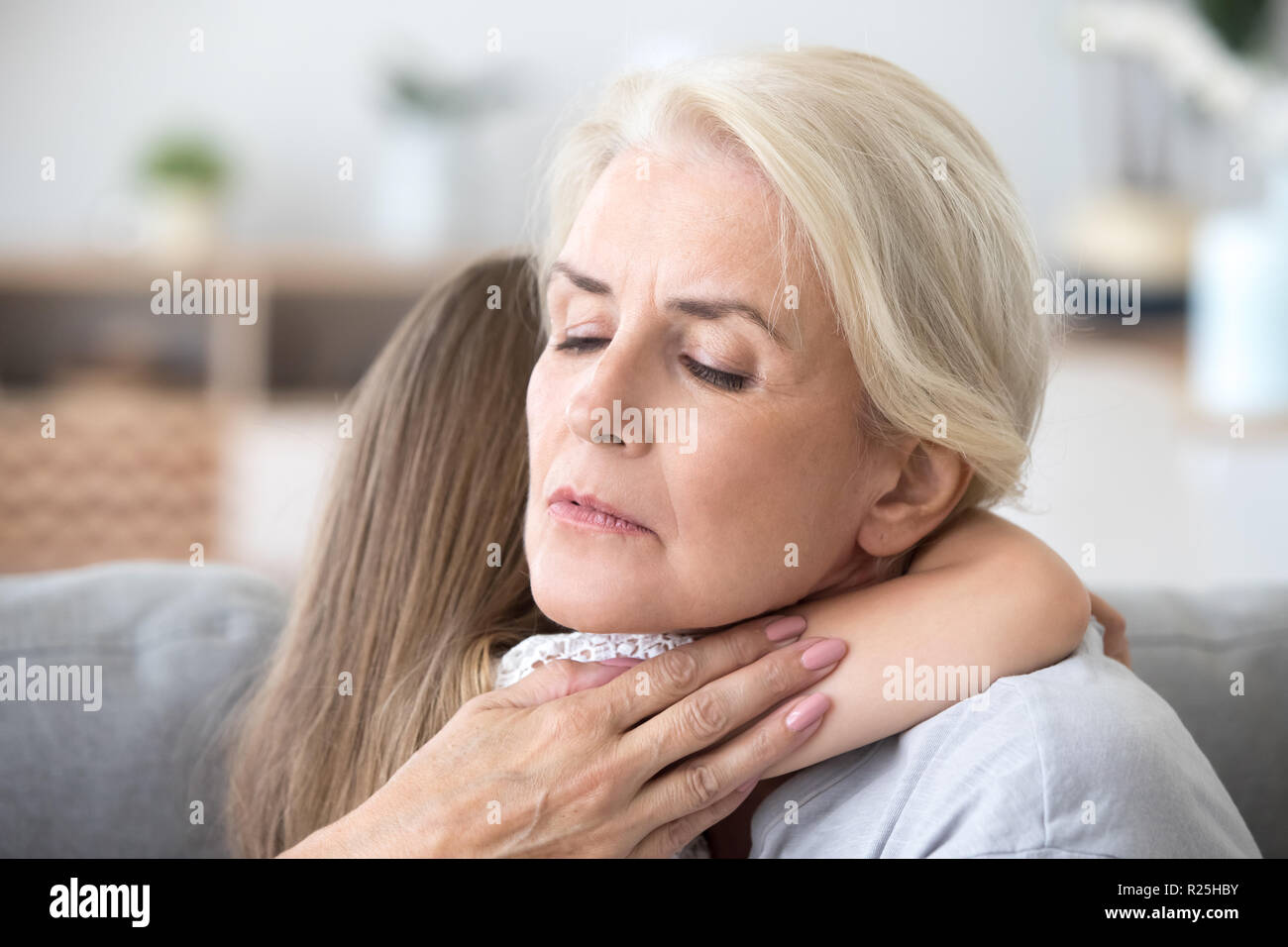 Loving sad grandmother embracing little girl comforting supporti Stock Photo