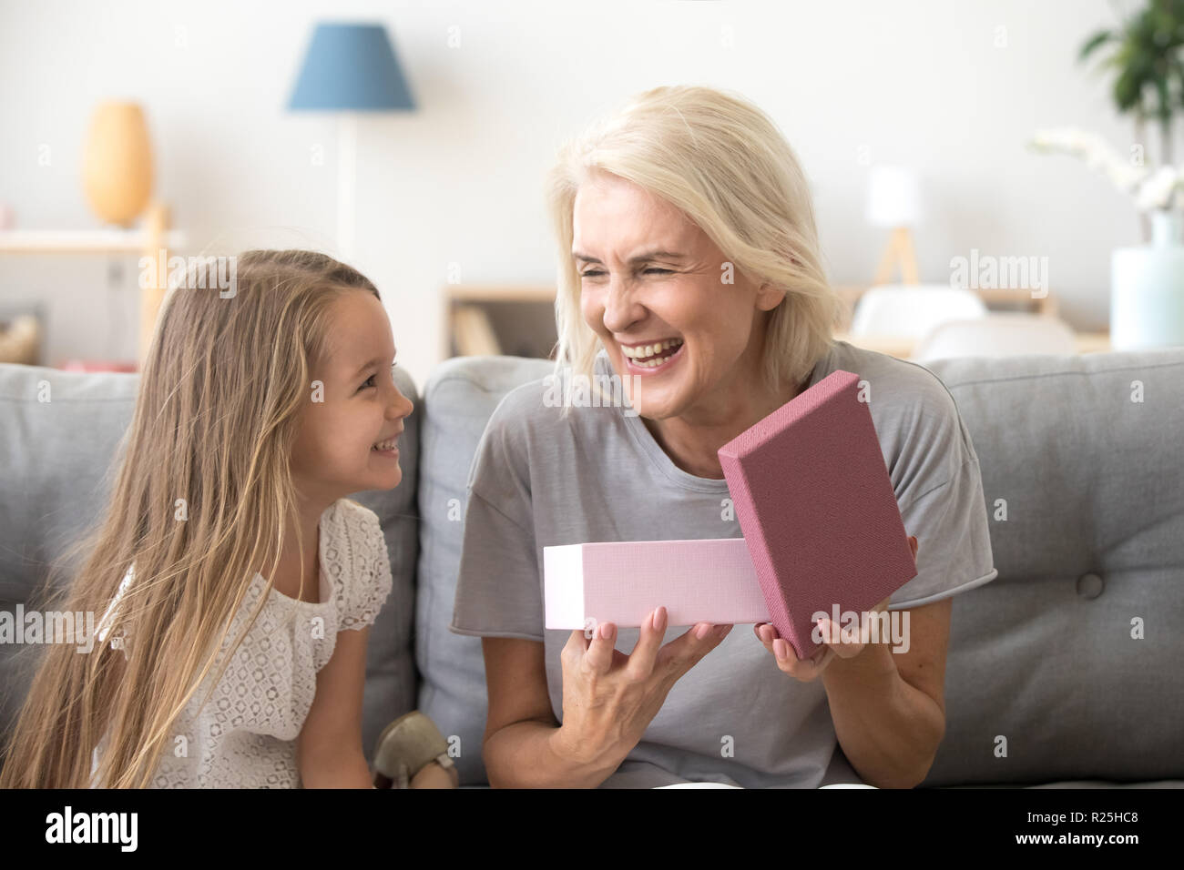 Happy grandmother opening gift box with present from grandchild  Stock Photo
