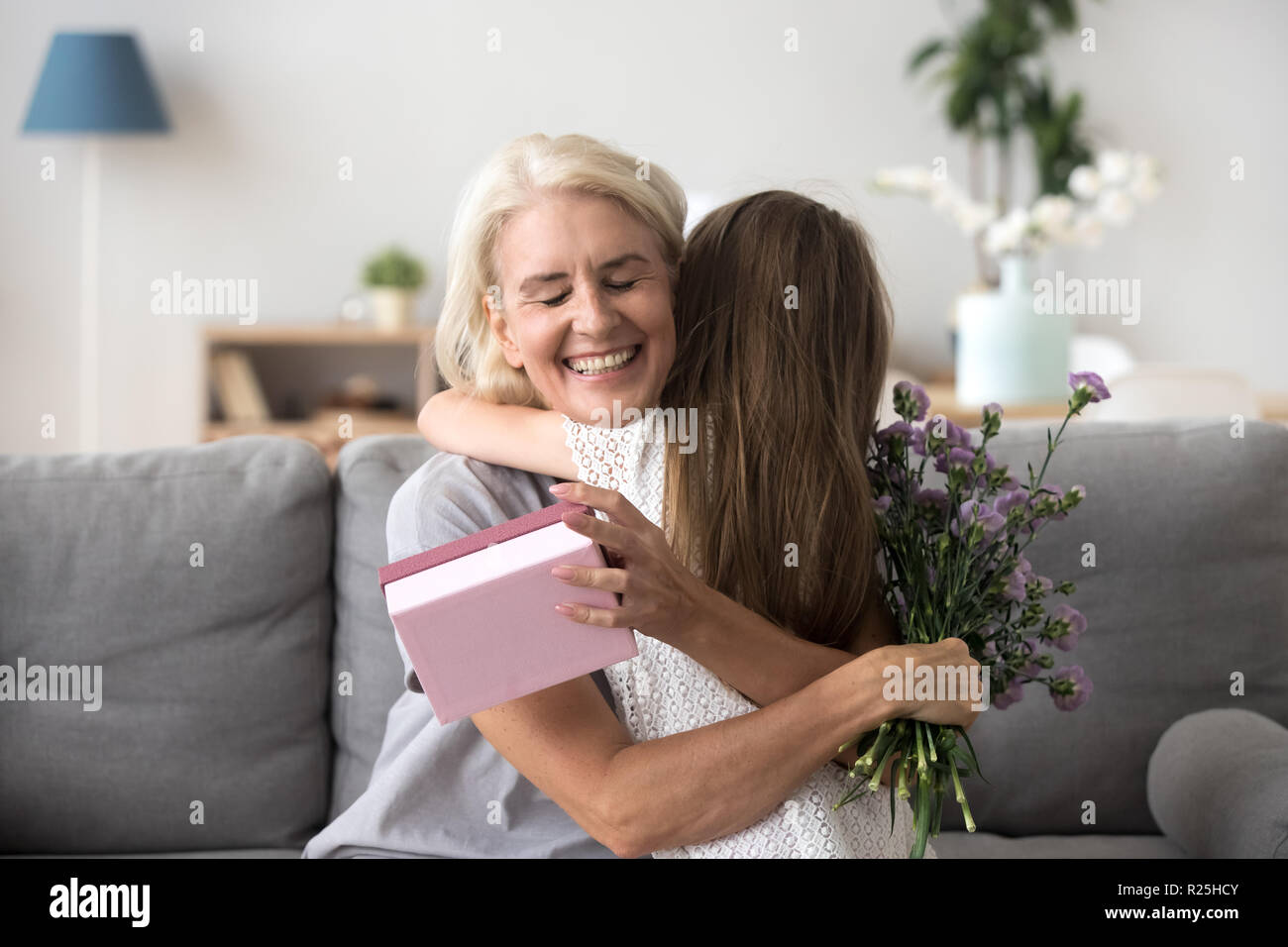 Happy senior grandma hugging granddaughter thanking for gift and Stock Photo