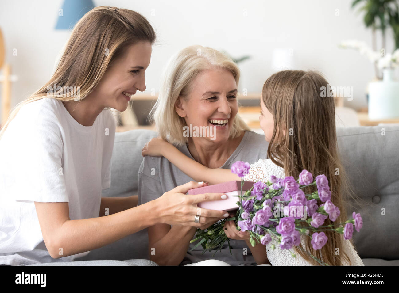 Happy grandma thanking grandchild and grown daughter for flowers Stock Photo