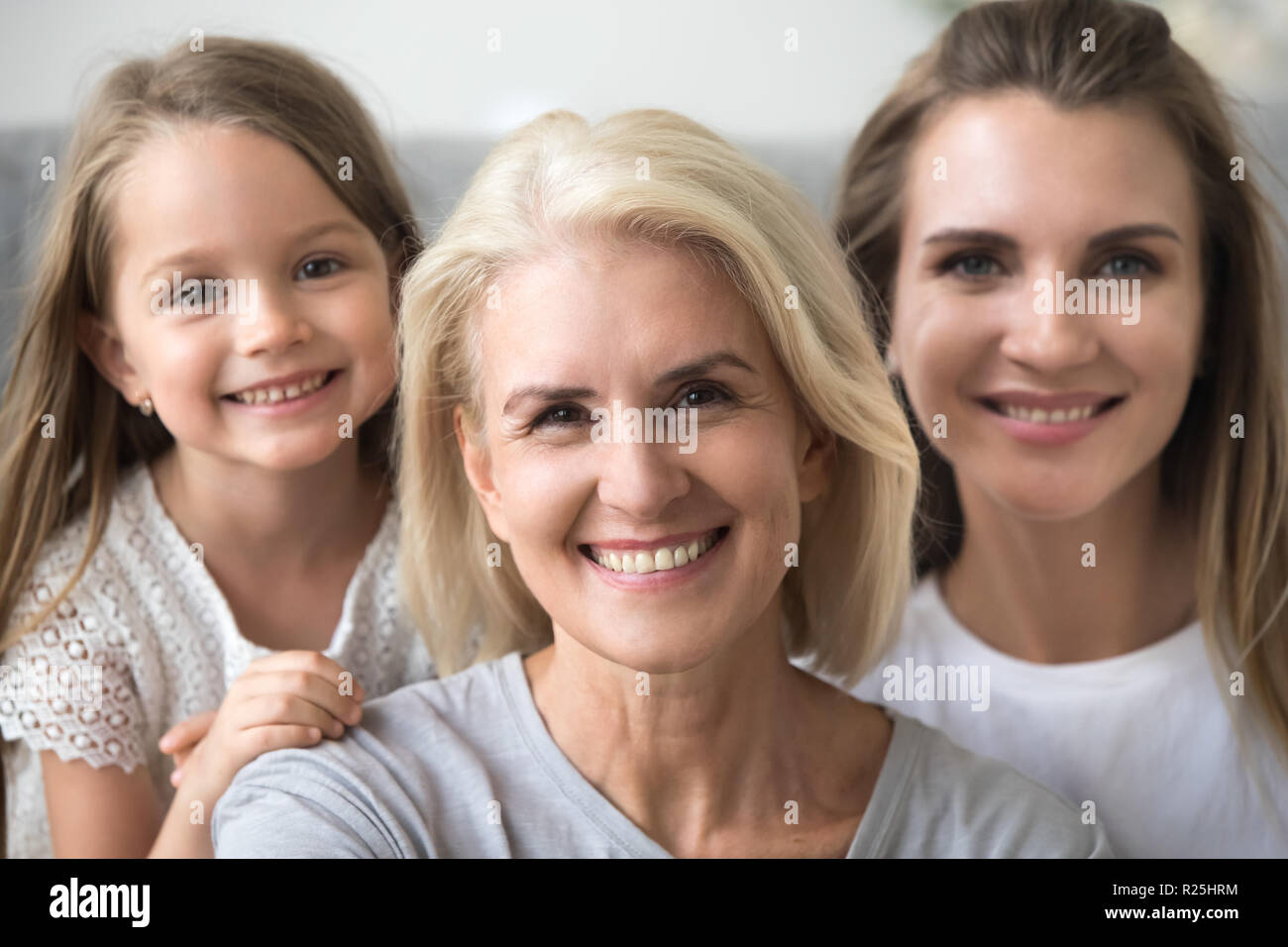Smiling senior grandmother looking at camera with daughter and g Stock Photo