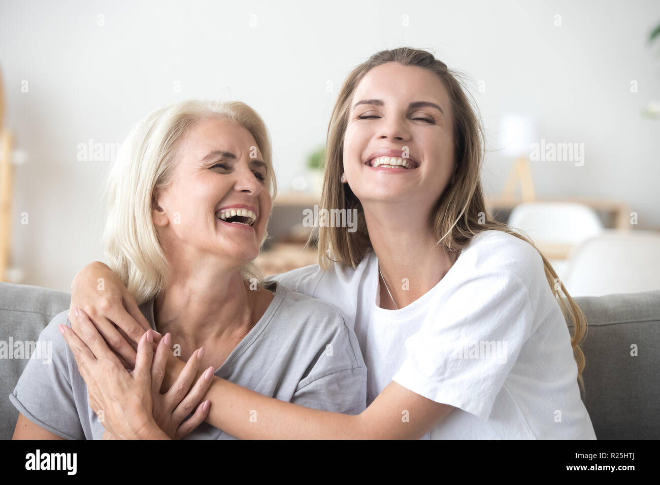 Happy senior mature mother embracing young adult woman laughing  Stock Photo
