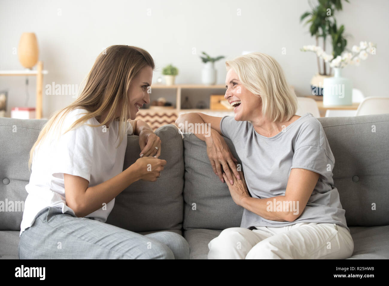 Cheerful old mother and young adult daughter talking laughing to Stock Photo