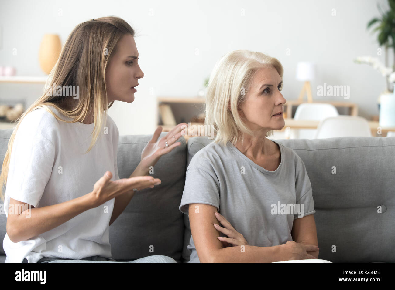 Annoyed adult daughter arguing with stubborn old mother ignoring Stock Photo