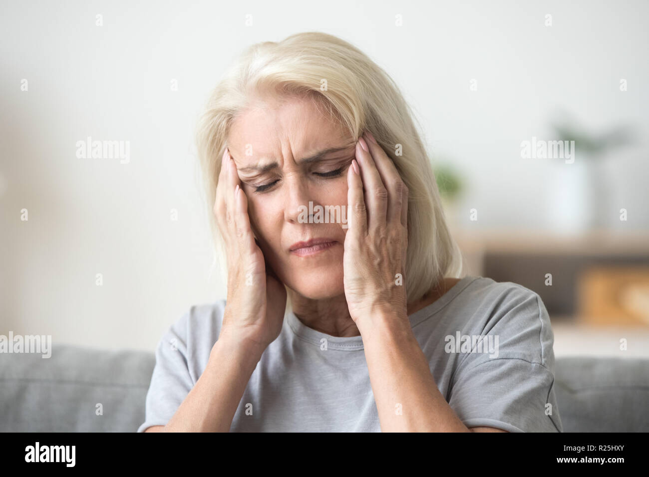 Upset older woman touching temples aching head feeling strong he Stock Photo