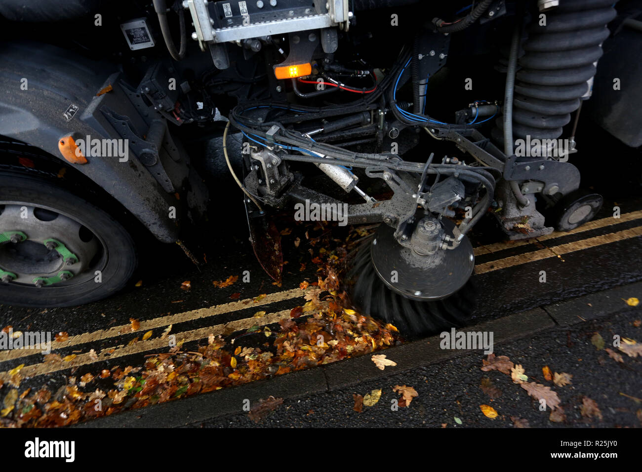 A council road sweeper pictured cleaning up leaves along the road in Chichester, West Sussex, UK. Stock Photo