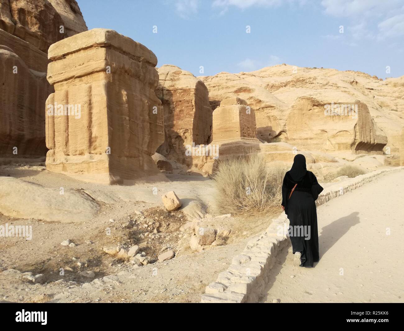 Petra, Jordan - October 19, 2018: An Arab woman walks past a sandstone temple in the historic city of Petra, Jordan. Stock Photo