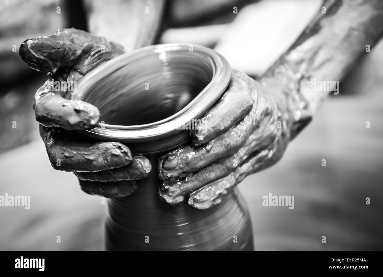 Hands of a man creating pottery on wheel, monochrome vintage view Stock Photo