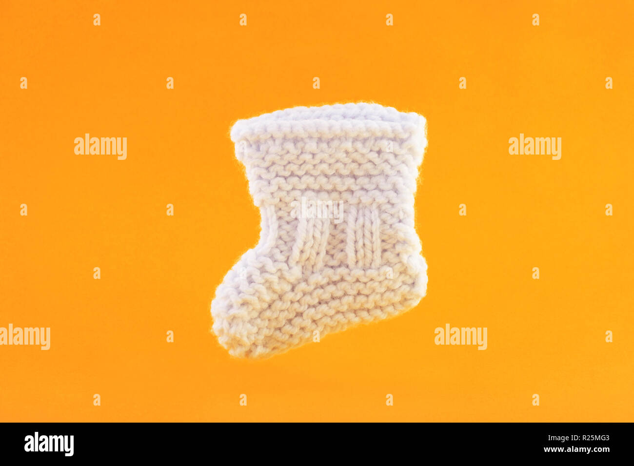 White baby sock on orange background Stock Photo