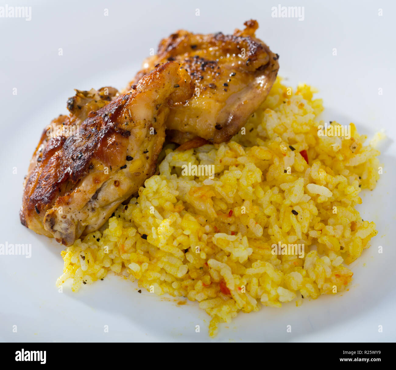 Delicious yellow rice with roasted chicken thighs on white ceramic ...