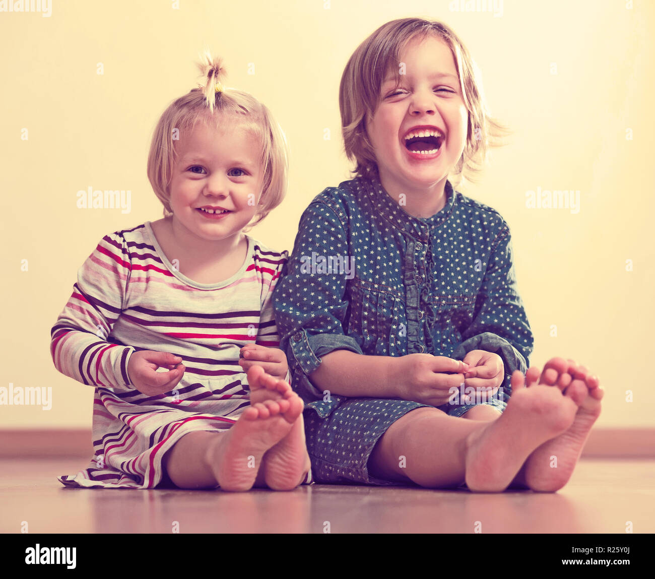 happy little girls sitting on the floor Stock Photo - Alamy