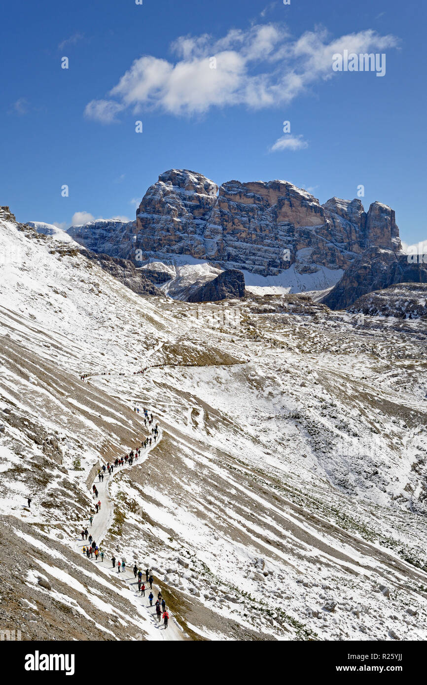 Hikers on the hiking trail 101 along the Three Peaks of Lavaredo South Walls towards Cappella degli Alpini Stock Photo