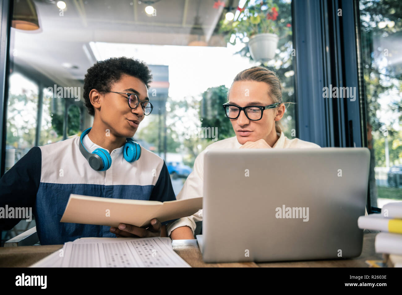 Serious young man helping his friend with exam preparation Stock Photo