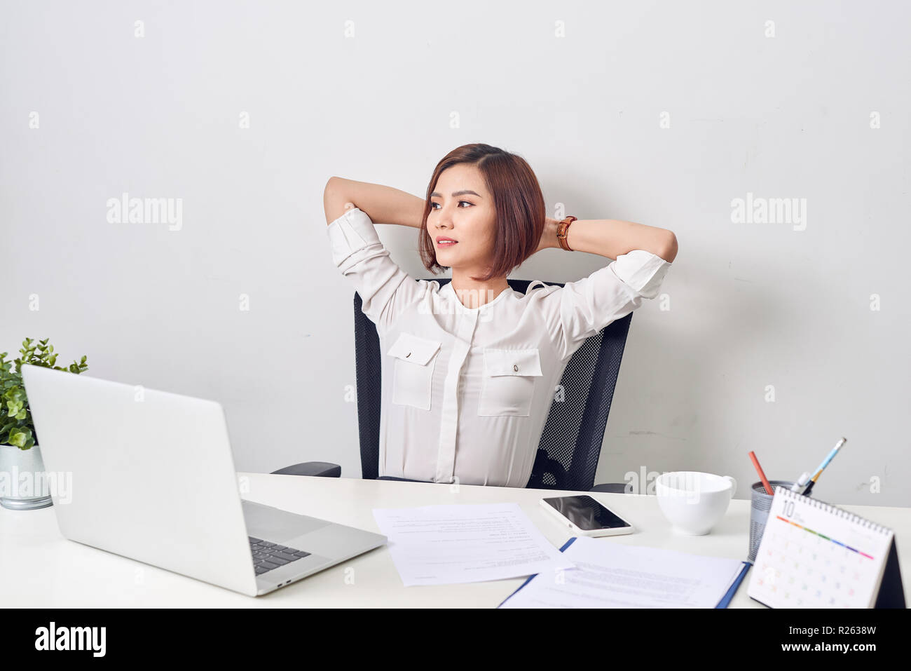 Business woman resting in the office after a working day leaning back her hands behind her head Stock Photo